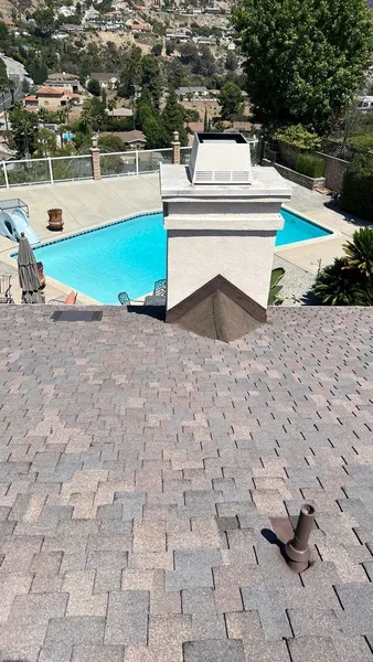 An image showing a backyard with a swimming pool, surrounded by a brick patio and landscaping.